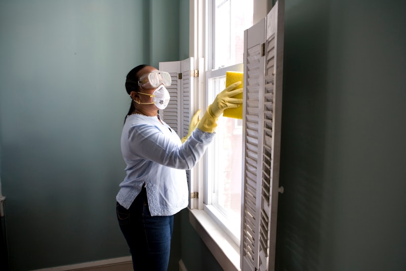 A caddy of cleaning supplies with spray bottles, cloths, and rubber gloves on a counter.
