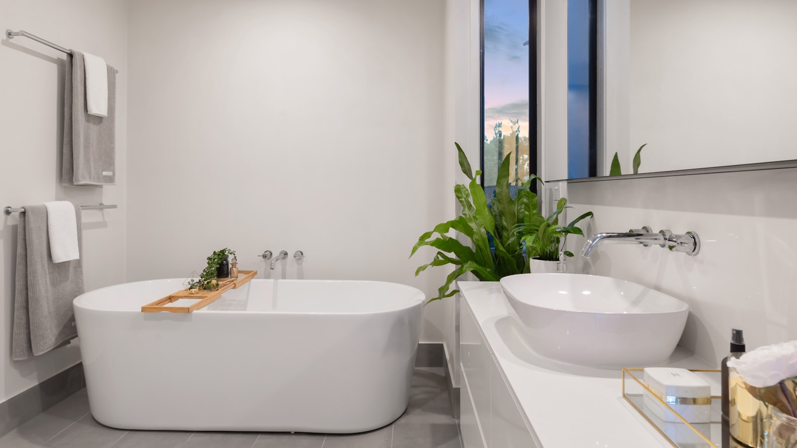 A clean, bright bathroom with a white sink, mirror, and tiled wall.