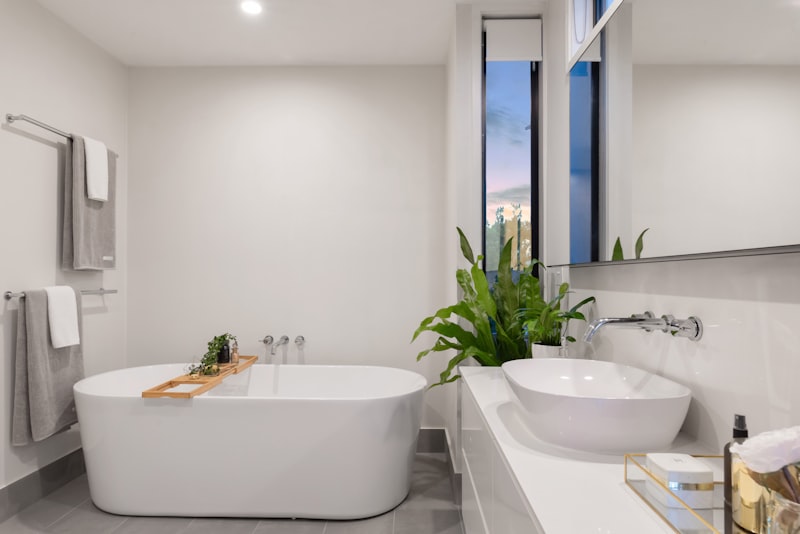 A clean, bright bathroom with a white sink, mirror, and tiled wall.